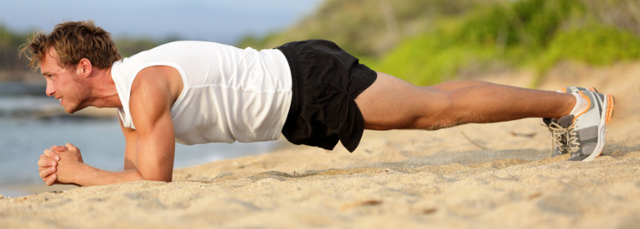 A man doing the plank exercise on the beach