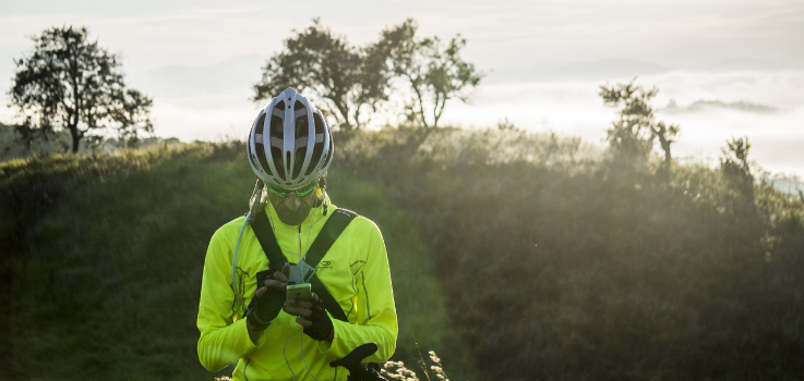 A cyclist wearing a helmet takes a break and checks his phone