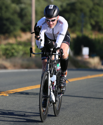 A male triathlete riding a time trial bike outdoors