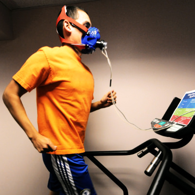 A person running on a treadmill wearing a face mask while taking a Vo2 max test indoors 