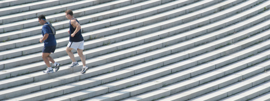 Two male runners doing a workout on a large set of stone steps