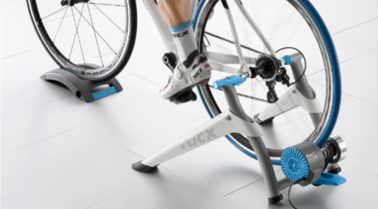 A photograph of the Tacx Flow Smart bike trainer with a road bike attached and a person riding it