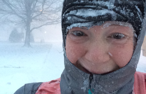 A photograph of a woman outdoors in a winter storm with ice on her clothing