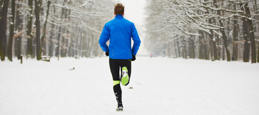 A photograph of a male running outdoors in snow