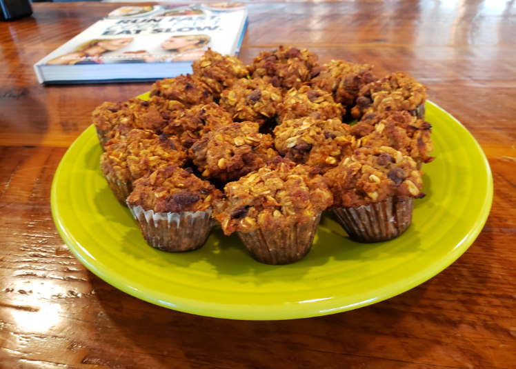 A green ceramic plate filled with apple and carrot mini-muffins