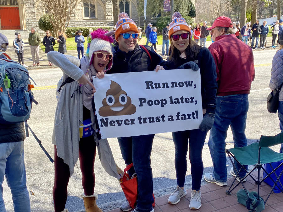 Spectators at a running race with a humorous sign to cheer on the runners 