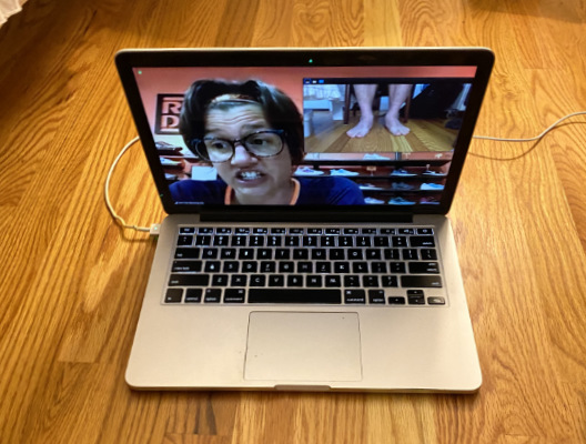 A photograph of a laptop on a floor with a Zoom video call between a running shoe expert and a client