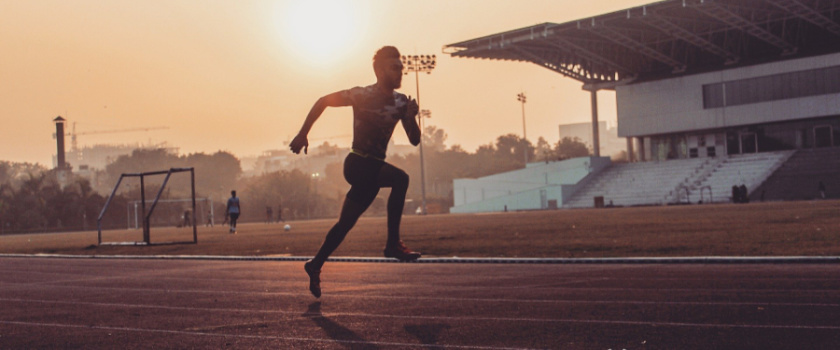 A male runner on a running track at sunset