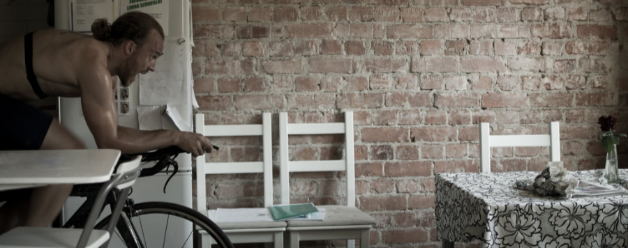 A male cyclist riding an indoor bike trainer in a kitchen